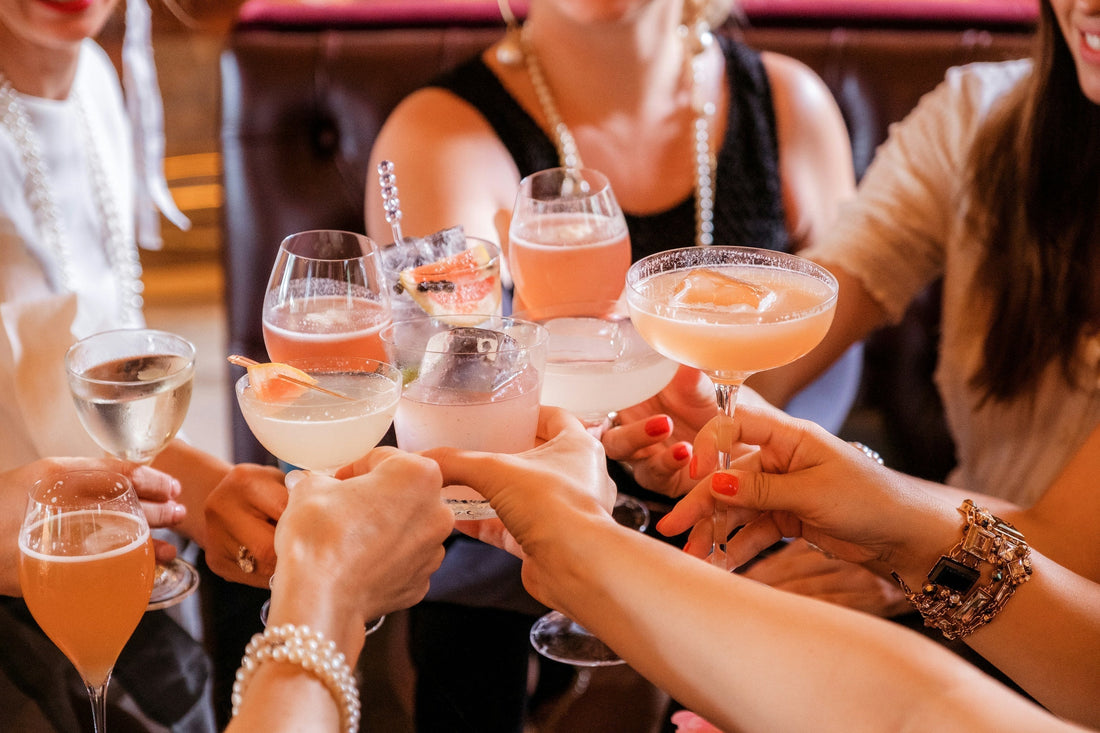 Group of friends clinking cocktail glasses during a celebration—capturing a festive moment where Aldicom can help prevent next-day hangovers.