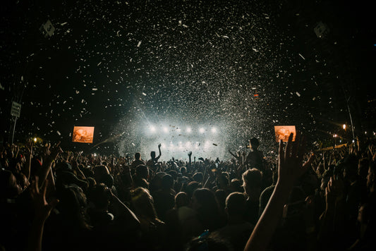Nighttime music festival crowd cheering under falling confetti and bright stage lights—capturing party energy where Aldicom can help you recover for the next day