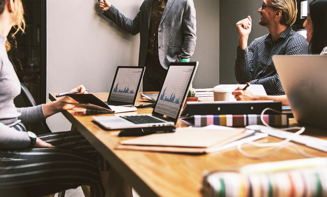 Professionals in a business meeting with laptops and data charts—highlighting the importance of staying sharp at work, supported by Aldicom for post-drinking recovery.