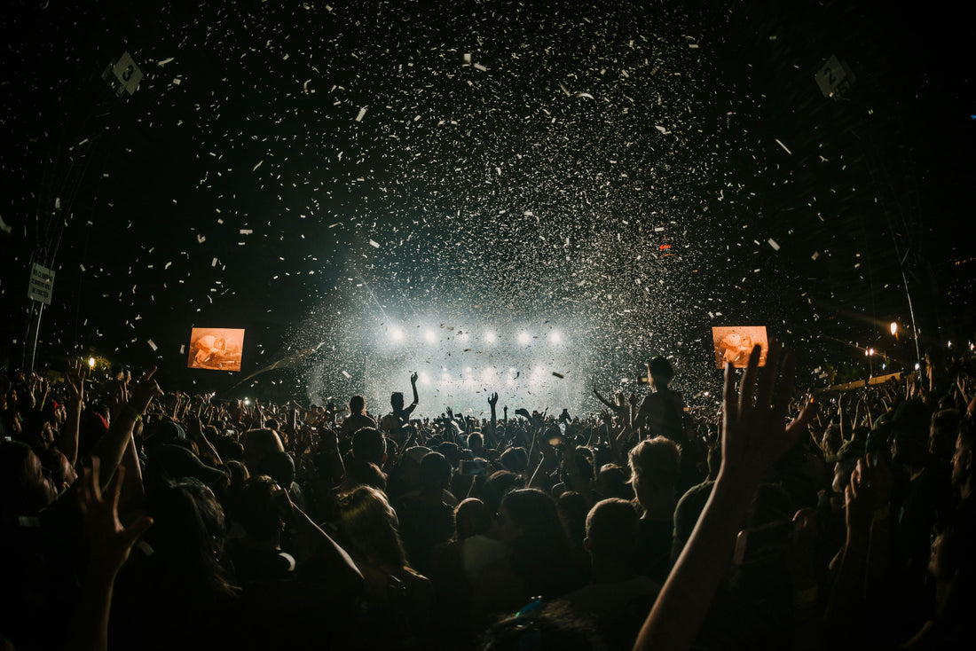 Nighttime music festival crowd cheering under falling confetti and bright stage lights—capturing party energy where Aldicom can help you recover for the next day