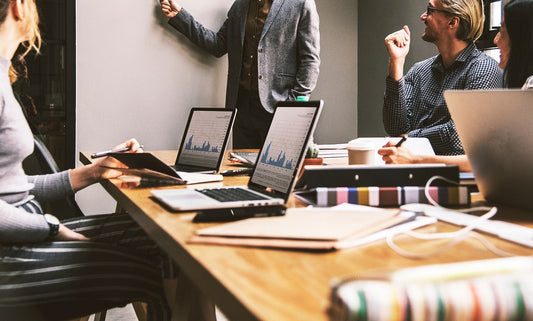 Professionals in a business meeting with laptops and data charts—highlighting the importance of staying sharp at work, supported by Aldicom for post-drinking recovery.